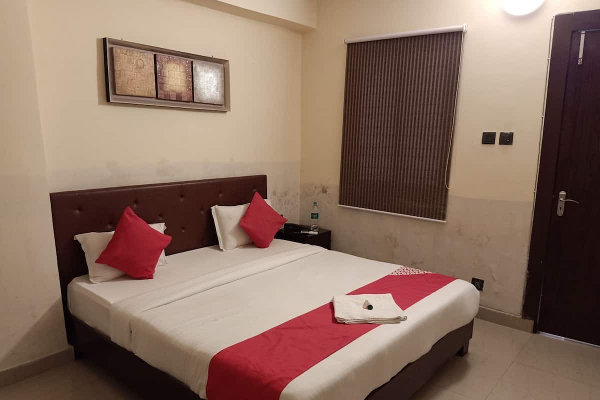 A neatly made bed with a red and white bedspread, a wooden headboard, and a single pillow.