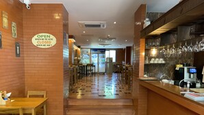 L’intérieur d’un restaurant avec des murs en briques, des tables et des chaises en bois, un sol carrelé et un comptoir avec une machine à café.