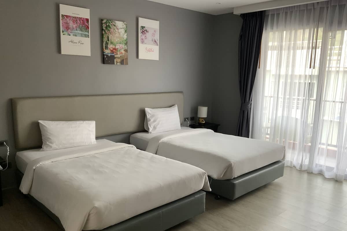 Een hotelkamer met twee bedden, een nachtkastje, een lamp en drie ingelijste foto’s aan de muur.