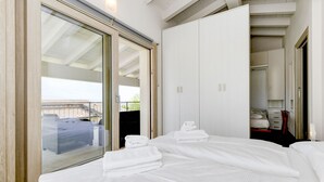 Una habitación de hotel con una cama, un armario y un ventanal corredero que da a un balcón.
