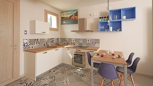 A compact kitchen with a dining area, featuring a tiled backsplash, a built-in oven, and a small dining table with chairs.
