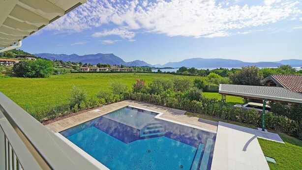 A swimming pool with a view of mountains and a lake. - Gardaliva5: with lake view in new residence with pool near to the lake (Manerba del Garda)