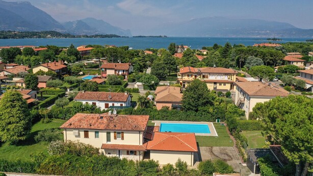 A residential area with houses, a swimming pool, and a view of the sea and mountains. - villa sole: with private pool near to the beach (Manerba del Garda)