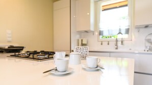 A clean, modern kitchen with white appliances and a central island with two white cups and saucers. - villa sole: with private pool near to the beach (Manerba del Garda)