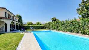 A swimming pool with a clear blue water, surrounded by a well-maintained lawn and a hedge. - villa sole: with private pool near to the beach (Manerba del Garda)