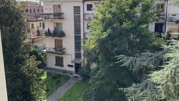 A multi-story residential building with balconies, a paved pathway, and surrounding greenery. - Venice Sweet Home (Venice)