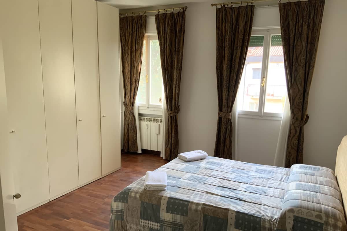 A bedroom with a bed, a wardrobe, and a window with curtains.