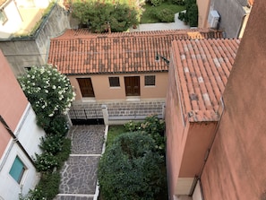 A courtyard with a tiled roof, stone pathway, and a small garden area with shrubs and flowers. - Venice Sweet Home (Venice)