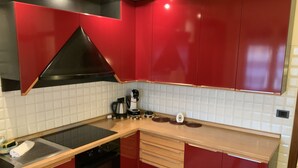 A kitchen with red cabinets, a black stove, and a white tiled backsplash. - Venice Sweet Home (Venice)