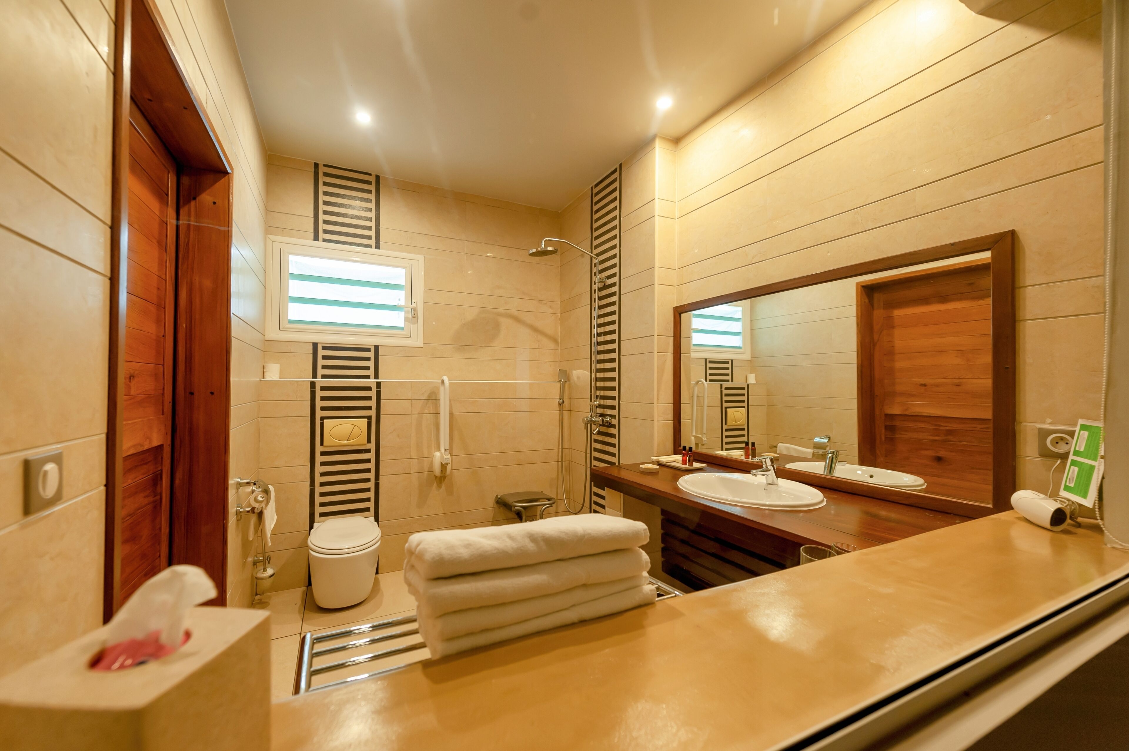 A modern bathroom with a wooden vanity, a large mirror, a toilet, and a shower.