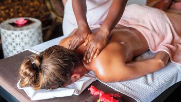 A person receiving a back massage on a massage table with a towel and a flower on the side.