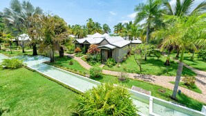 A resort with multiple bungalow-style buildings, a swimming pool, and lush tropical landscaping. - Palm Beach Resort & Spa (Nosy Be)