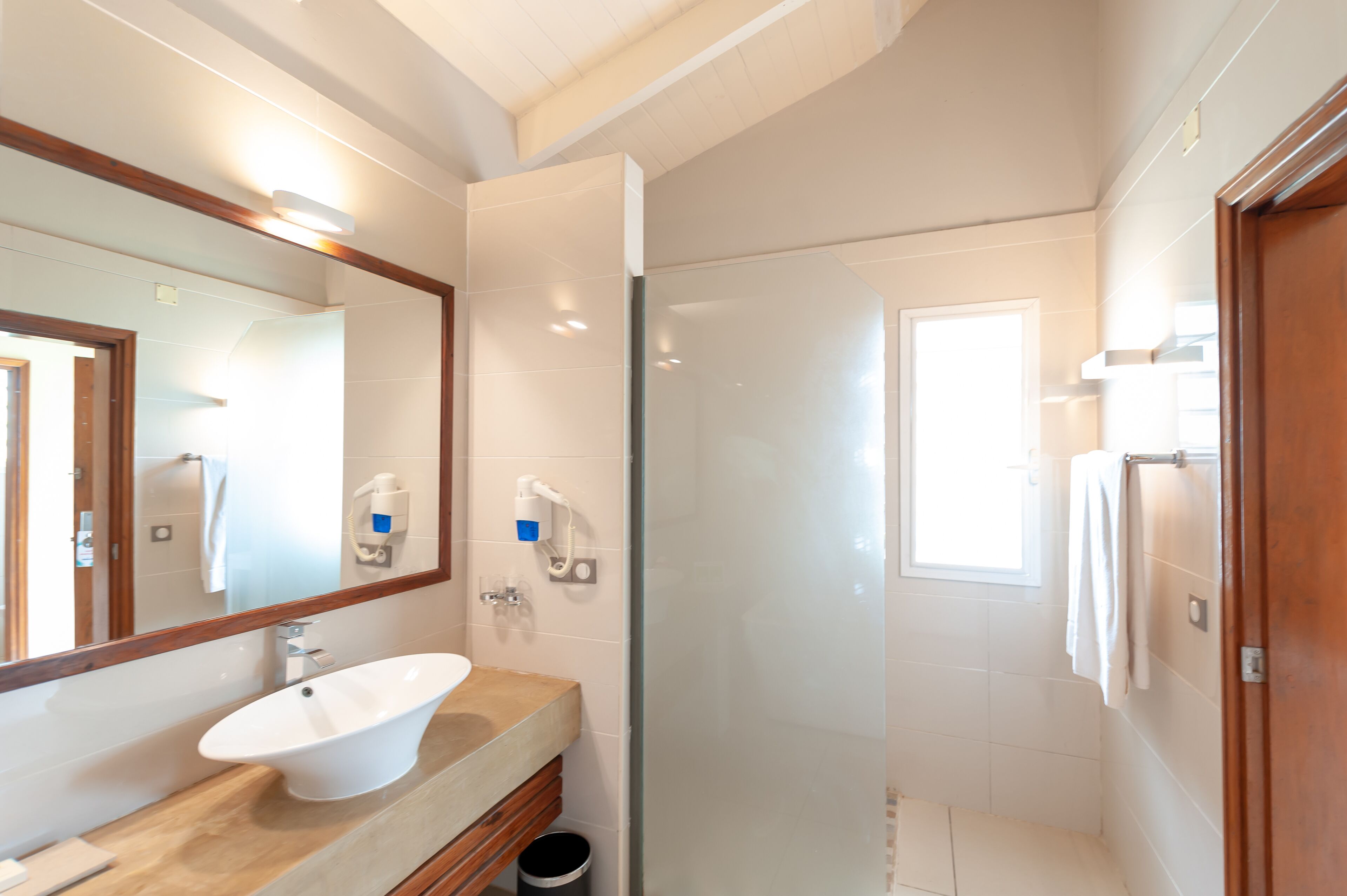 Un baño moderno con un lavamanos independiente, una cabina de ducha de vidrio y un espejo grande.