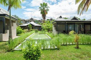 A resort with modern villas, a central pool, and lush greenery.