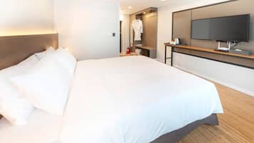 A hotel room with a large bed, a TV mounted on the wall, and a wooden bedside table.