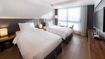 A hotel room with two beds, a TV, a desk, and a chair.