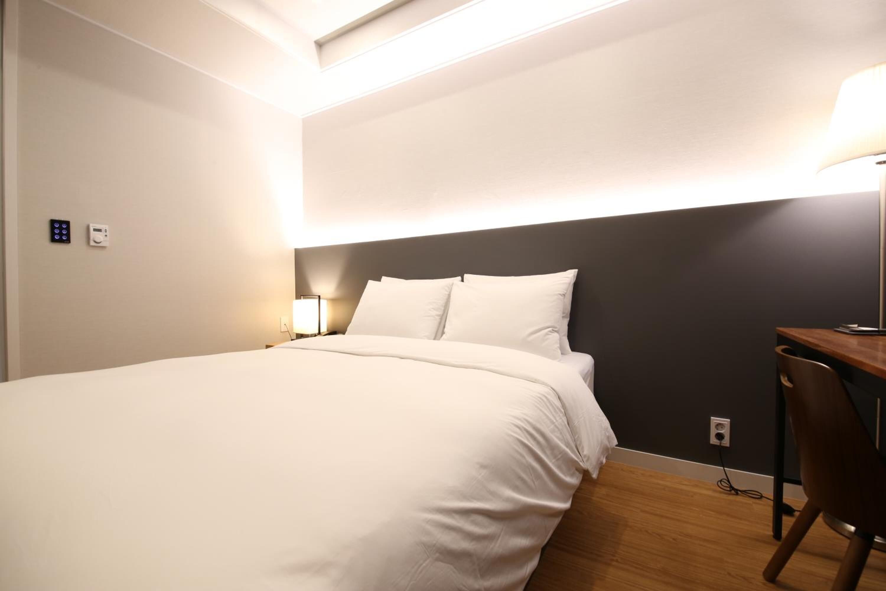 A hotel room with a large bed, a desk, and a chair.