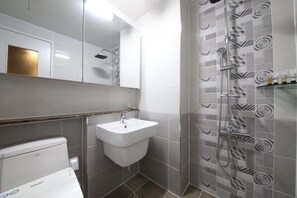 A modern bathroom with a white sink, a shower with a patterned tile wall, and a toilet. - The Mains Hotel (Cheonan)