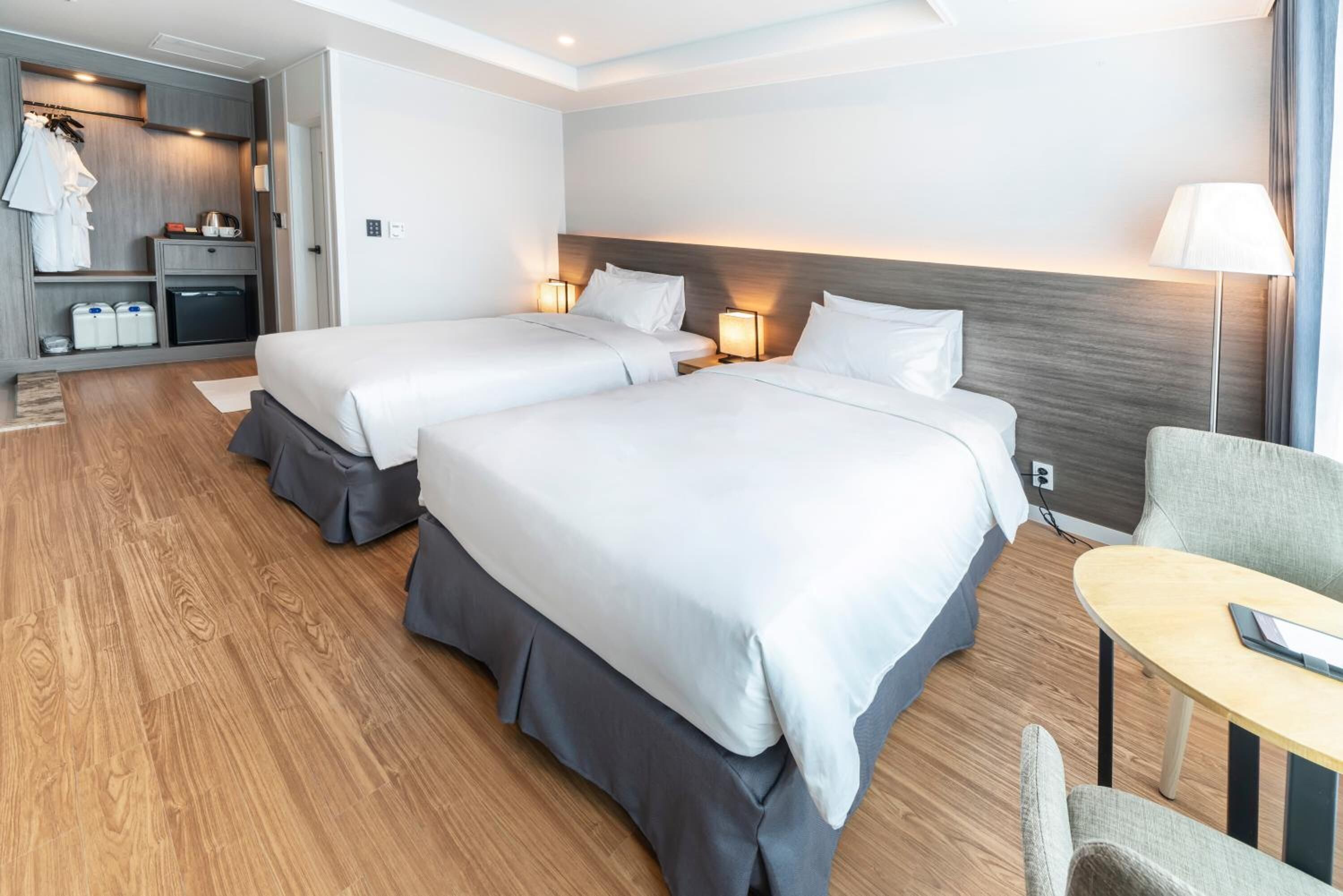 A hotel room with two beds, a desk, and a seating area.