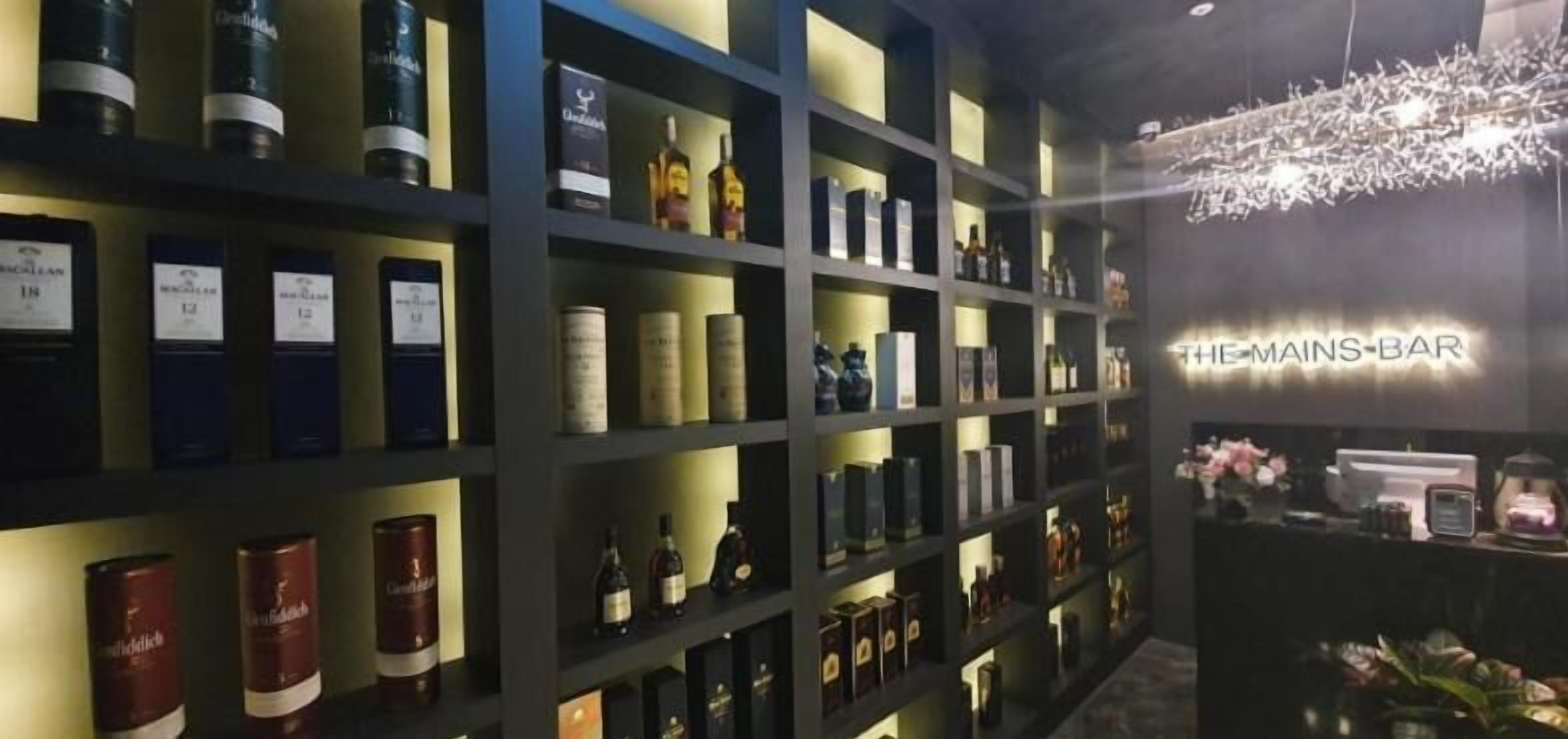 A bar area with shelves of liquor bottles and a sign reading "THE MAINS BAR".