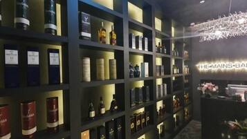 A bar area with shelves of liquor bottles and a sign reading "THE MAINS BAR".