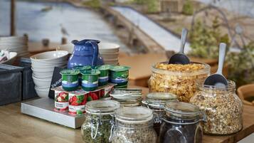 A breakfast buffet with various food items and a scenic seaside mural in the background.