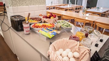 A breakfast buffet with various food items, a toaster, and a basket of eggs.