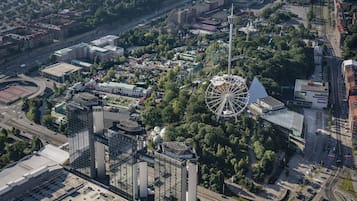 An aerial view of a cityscape with a prominent Ferris wheel, modern buildings, and a large stadium.