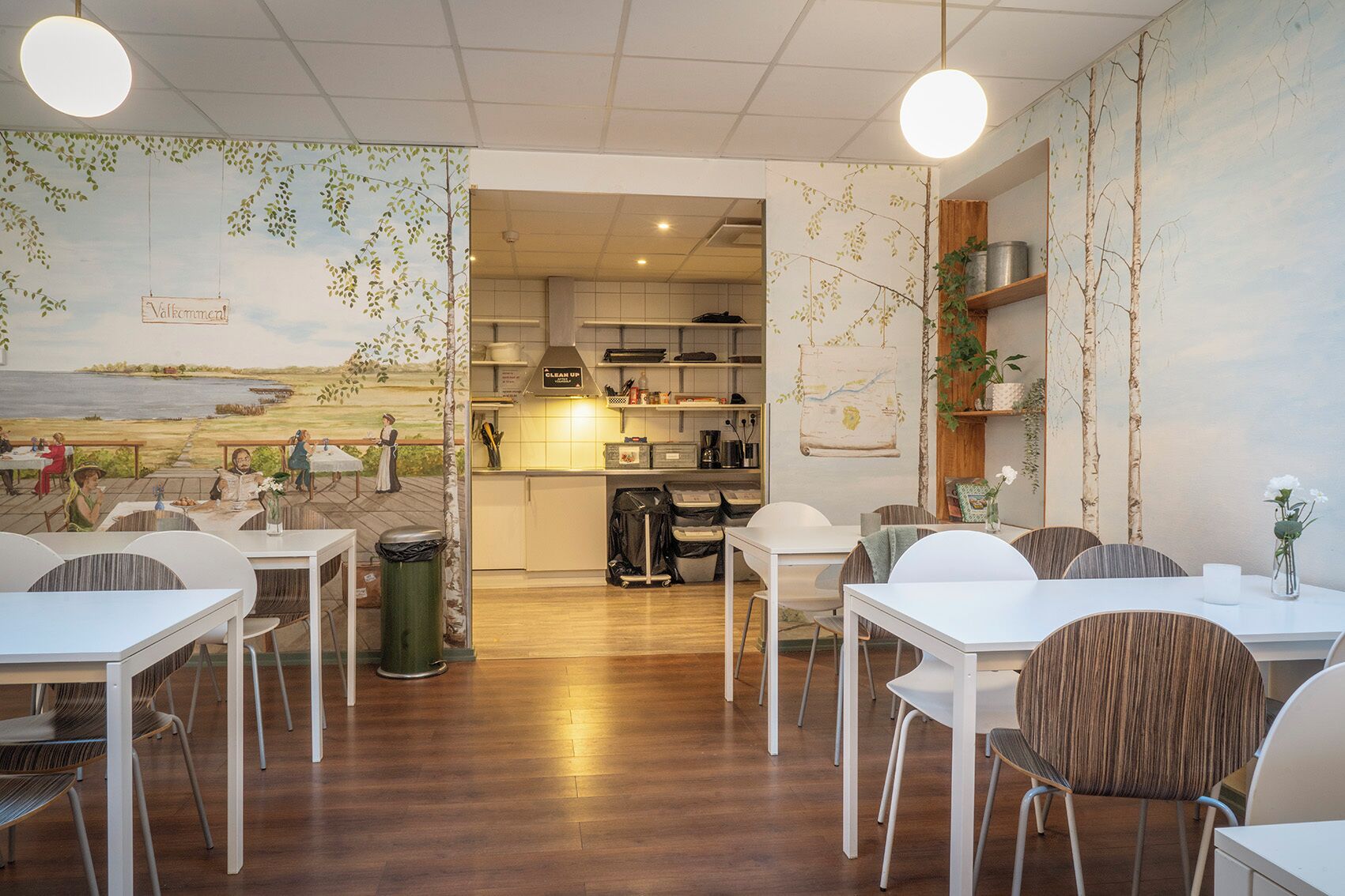 Un restaurant offrant une vue sur une fresque murale, doté d’un plancher en bois et de mobilier blanc.