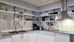 A modern kitchen with white cabinets, stainless steel appliances, and a range hood. - Göteborg Hostel (Gothenburg)