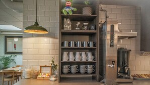 A modern kitchen with a built-in coffee machine, shelves with mugs, and a hanging light fixture. - Göteborg Hostel (Gothenburg)