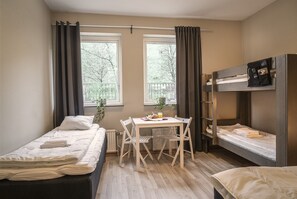 Cozy space with a bunk bed, single bed, and table with chairs, offering a view of the outdoors through two windows.