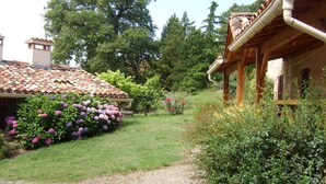 Un sendero en un jardín que conduce a una casa con techo de tejas y porche de madera.