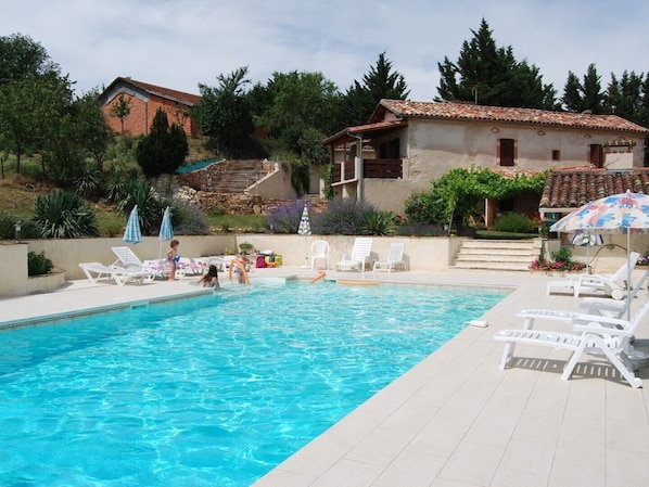 Una piscina con sillones de playa y sombrillas.