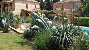 Una villa con piscina, rodeada de exuberante vegetación y un jardín cuidado.