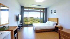 Een hotelkamer met een bed, een bureau, een televisie en een groot raam met uitzicht op de omgeving.