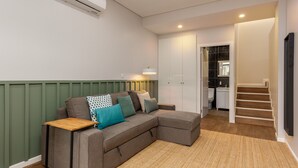 Ein modernes Wohnzimmer mit einem Ecksofa, einem kleinen Holztisch und einem gewebten Teppich.