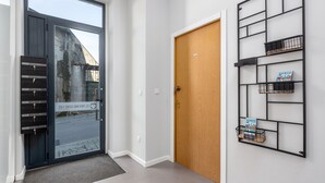 A modern entrance with a glass door, a wooden door, and a metal shelf with books. - Feel Porto Wine Essence II (Vila Nova de Gaia)