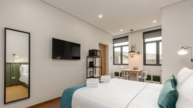 A modern hotel room with a large bed, a flat-screen TV, a desk with a chair, and a view of the outside. - Feel Porto Wine Essence II (Vila Nova de Gaia)