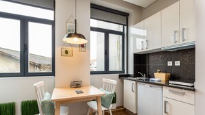 A modern kitchen with white cabinets, a black countertop, and a window with a view of the outside. - Feel Porto Wine Essence II (Vila Nova de Gaia)