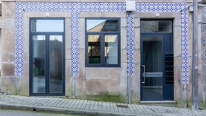 Een gebouw met drie grote glazen deuren en een gevel van tegels.
