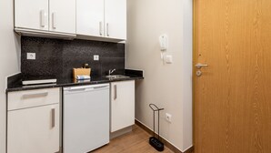 Een kleine keuken met witte kastjes, een zwart aanrecht, een vaatwasser en een houten deur.
