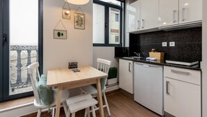 Eine moderne Küche mit weißen Schränken, einem Holztisch und Blick ins Freie durch ein großes Fenster.