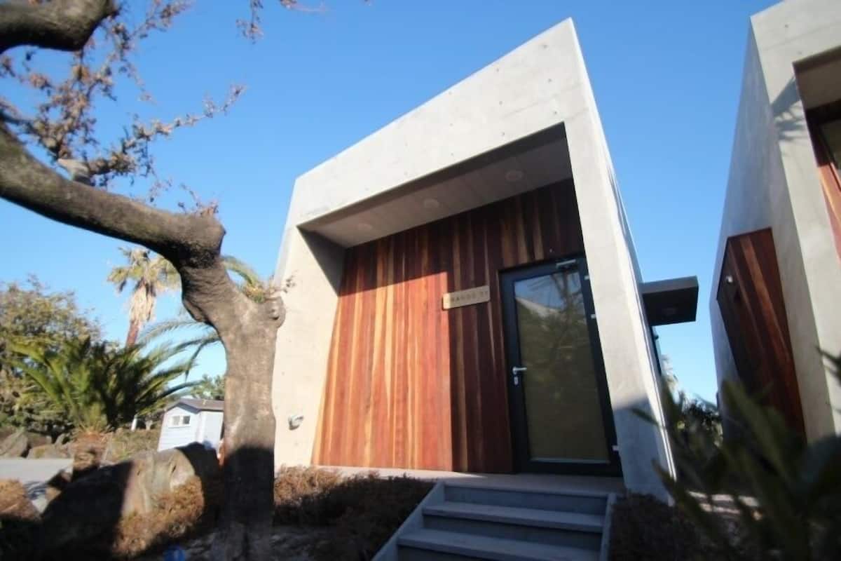 A modern building with a wooden door and a nameplate.