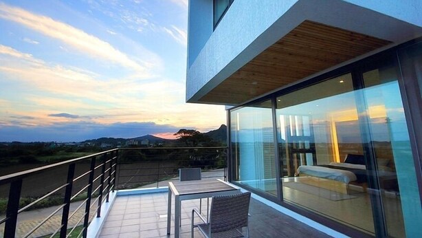 A modern building with a balcony overlooking a scenic landscape. - Villanoi Jeju (Seogwipo)