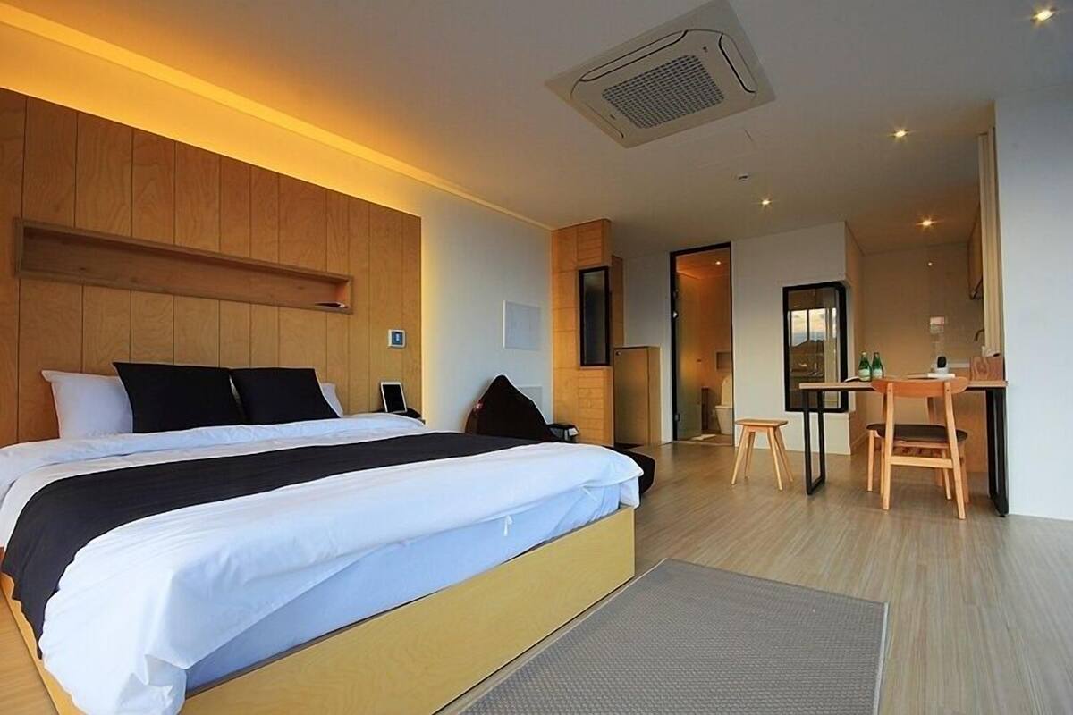 Ein modernes Hotelzimmer mit einem großen Bett, einem kleinen Schreibtisch und einer Sitzecke.