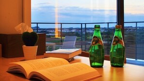 A desk with an open book, two green bottles, a potted plant, and a laptop. - Villanoi Jeju (Seogwipo)