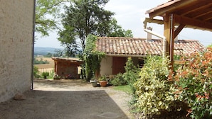 A rustic building with a tiled roof, a gravel path leading to it, and a view of the countryside. - the gites of Manavit-haut T3 (occitanie)