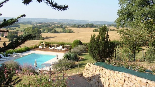 A pool area with lounge chairs and a stone wall. - the gites of Manavit-haut T3 (occitanie)
