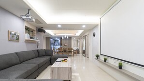 Ein modernes Wohnzimmer mit einem grauen Sofa, einem Holztisch und einem Essbereich mit Tisch und Stühlen.